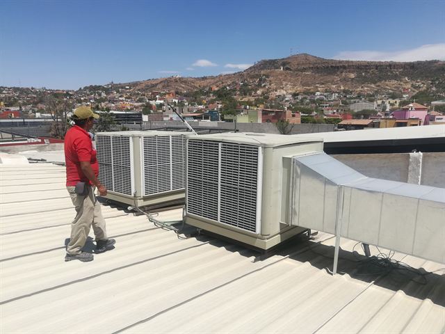 Técnico de AASMA revisando equipos de enfriamiento en el techo de un comercio