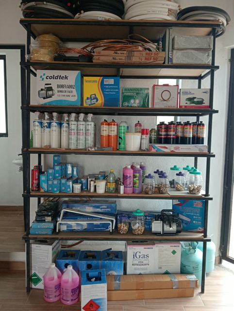 Anaquel con bombas de vacío, manómetros, gas refrigerante, capacitores y conexiones